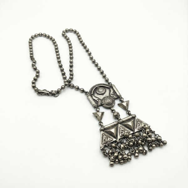 Silver necklace with geometric pendant and chain on a white background