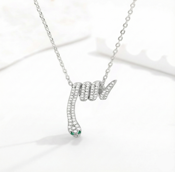 Silver snake-shaped pendant necklace with green gemstone on a white background