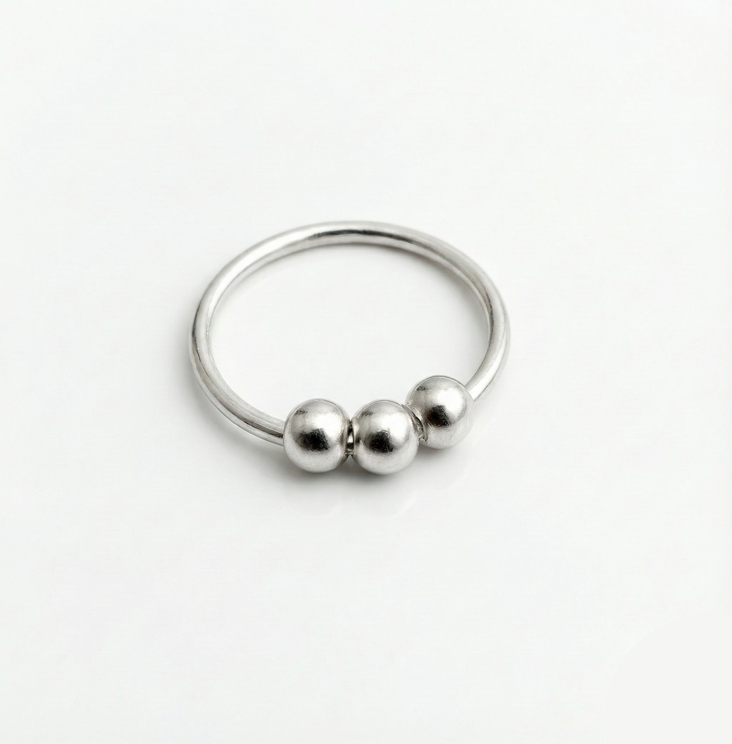Silver ring with three beads on a white background