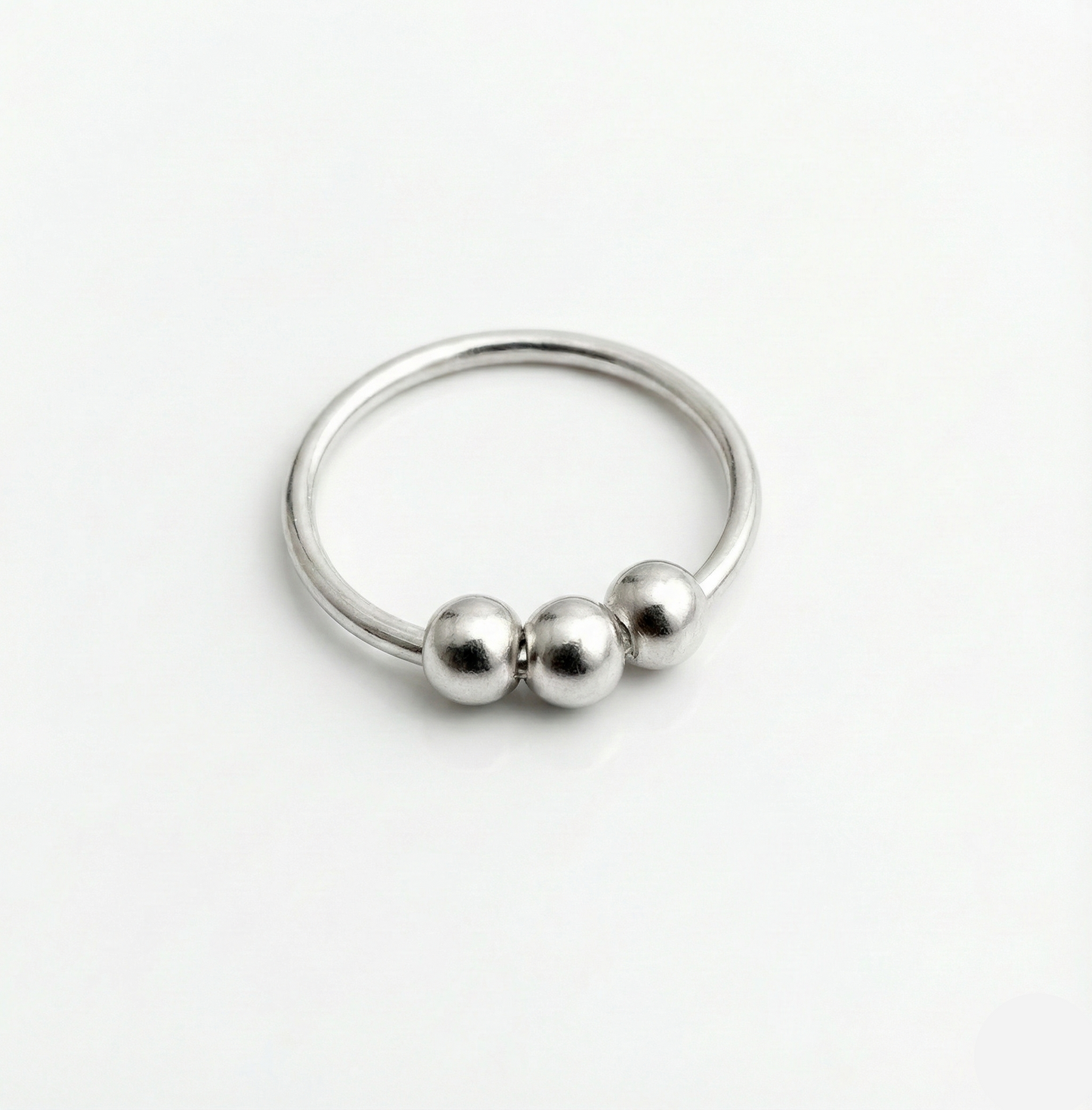 Silver ring with three beads on a white background