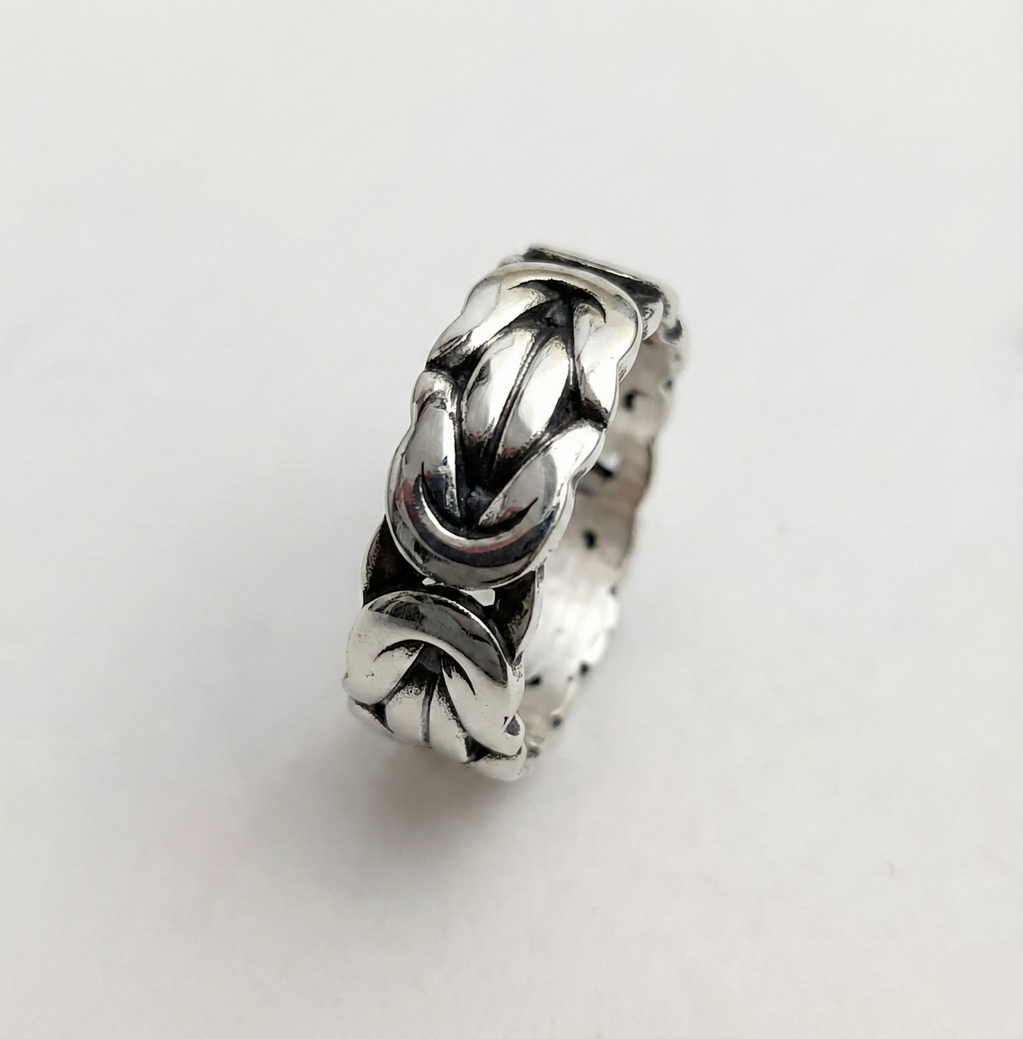 Silver ring with intricate design on a light gray background