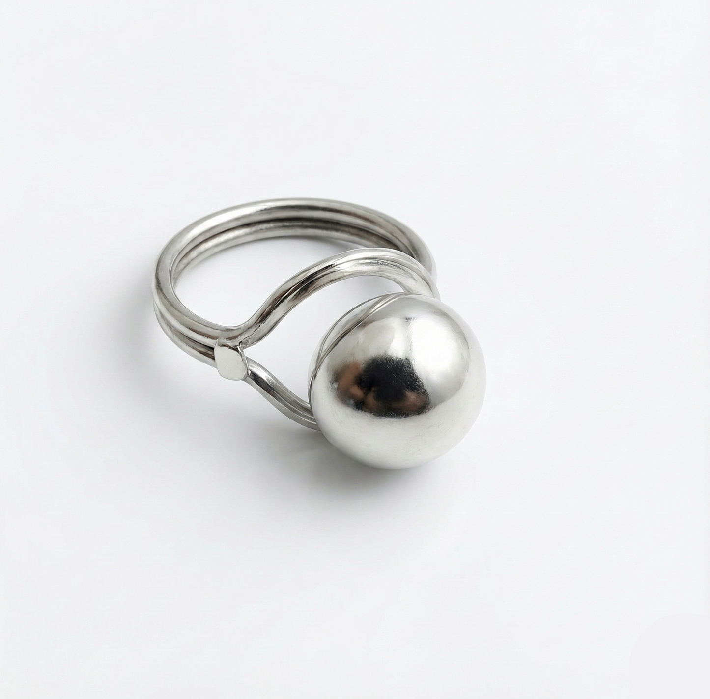 Silver ring with a spherical component on a white background