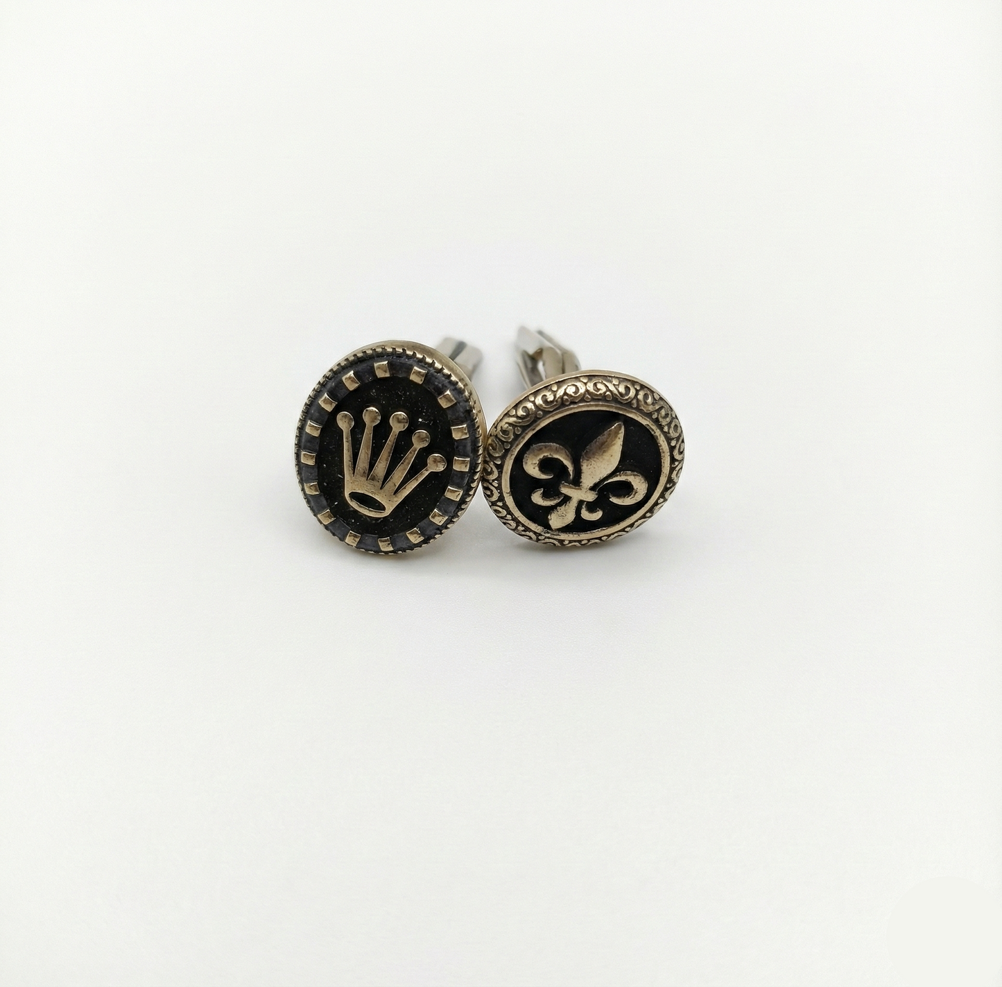 Pair of cufflinks with decorative symbols on a white background