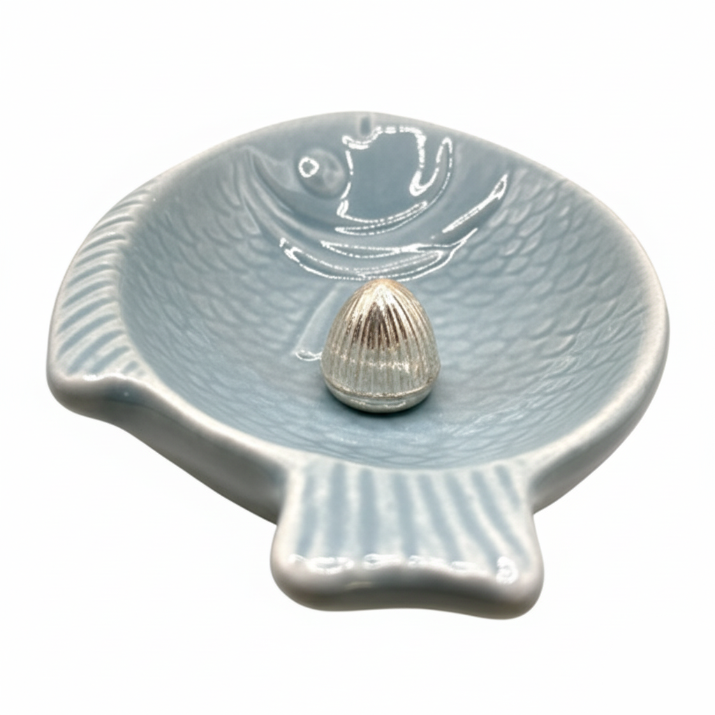 Ceramic shell-shaped dish with a small shell on a white background