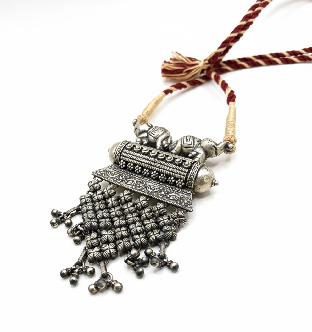 Ornate silver necklace with tassels on a white background