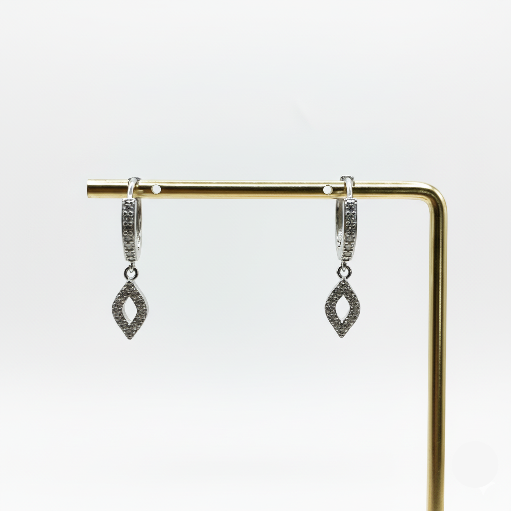 Pair of silver earrings on a gold stand against a white background