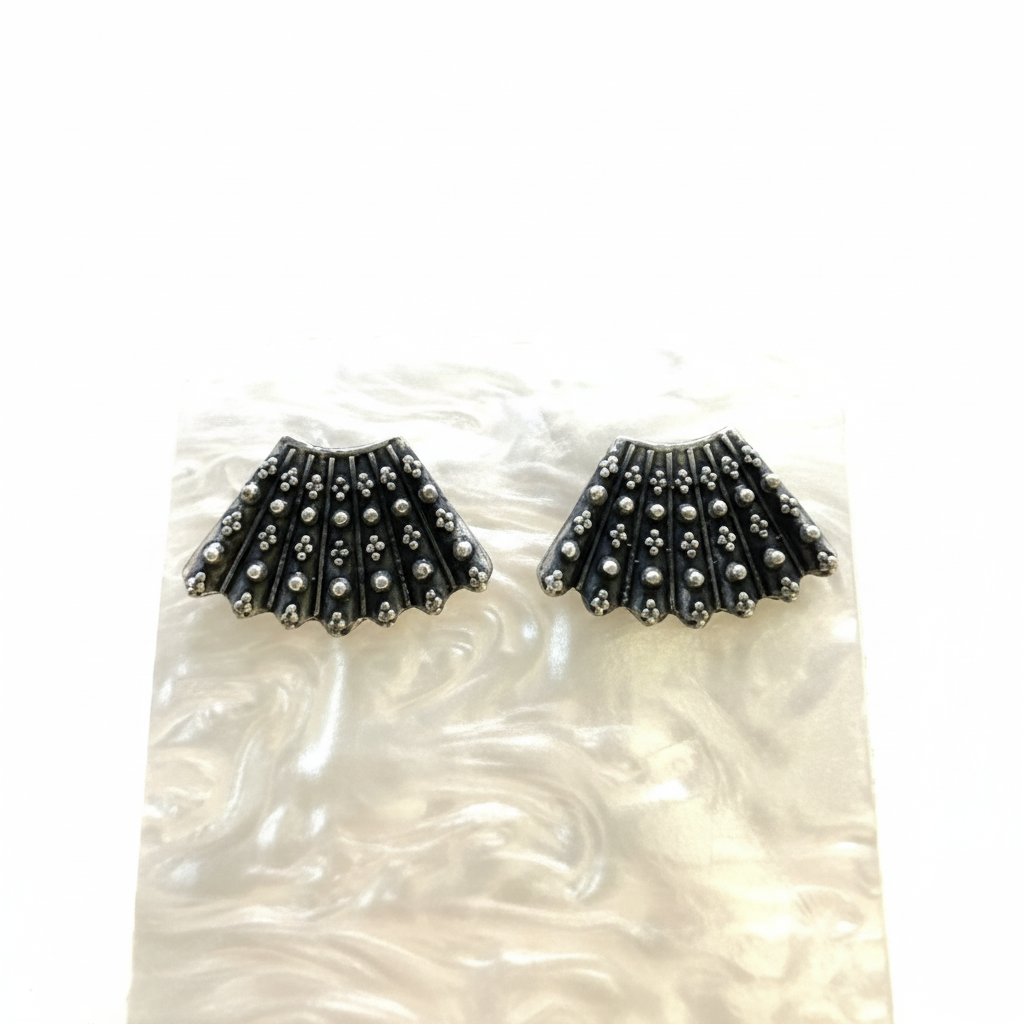 Black and silver earrings on a white shell background
