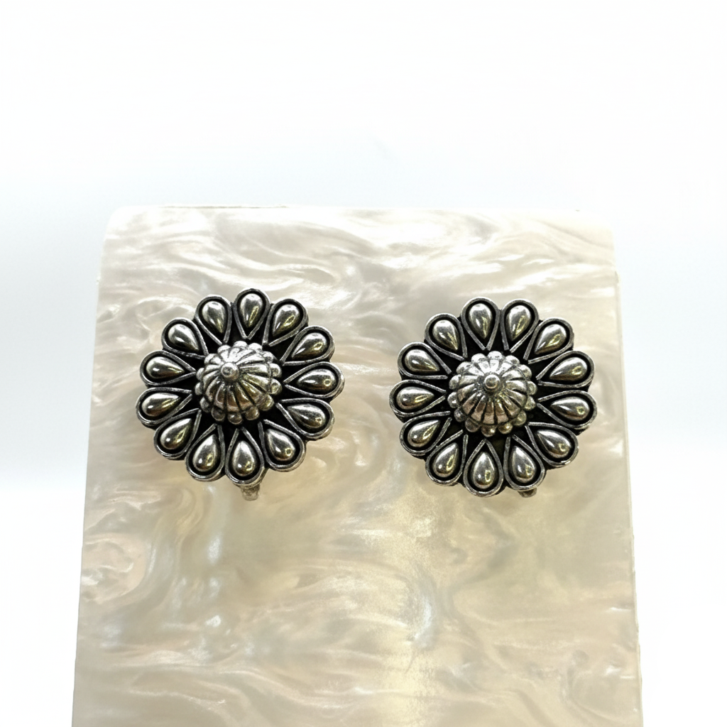 Pair of silver floral earrings on a textured white surface