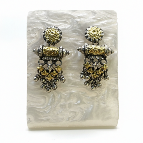 Pair of gold and silver earrings on a white stone surface