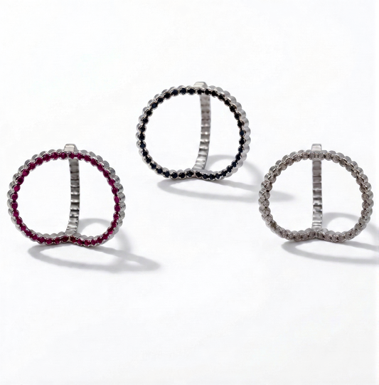 Three circular earrings with different gemstone colors on a white background