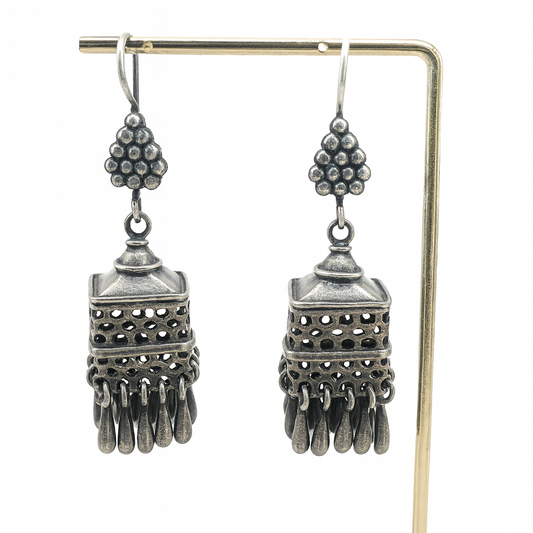 Pair of silver earrings with intricate designs on a white background