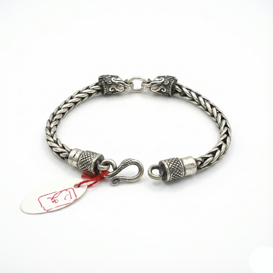 Silver braided bracelet with intricate designs on a white background