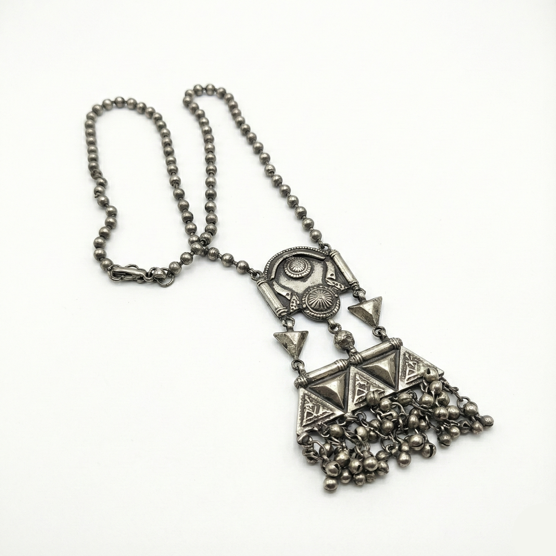 Silver necklace with geometric pendant and chain on a white background