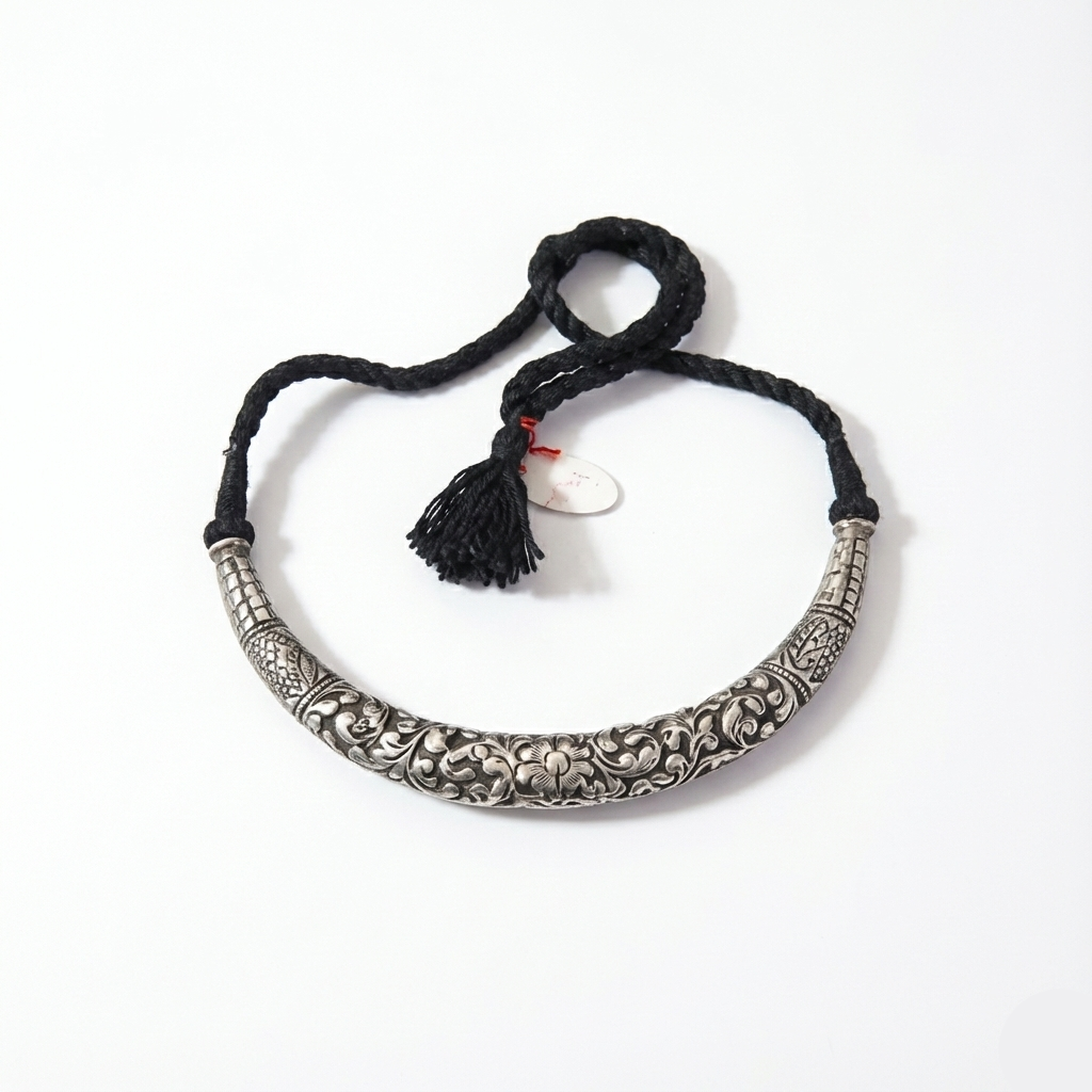 Silver necklace with intricate designs on a black cord against a white background