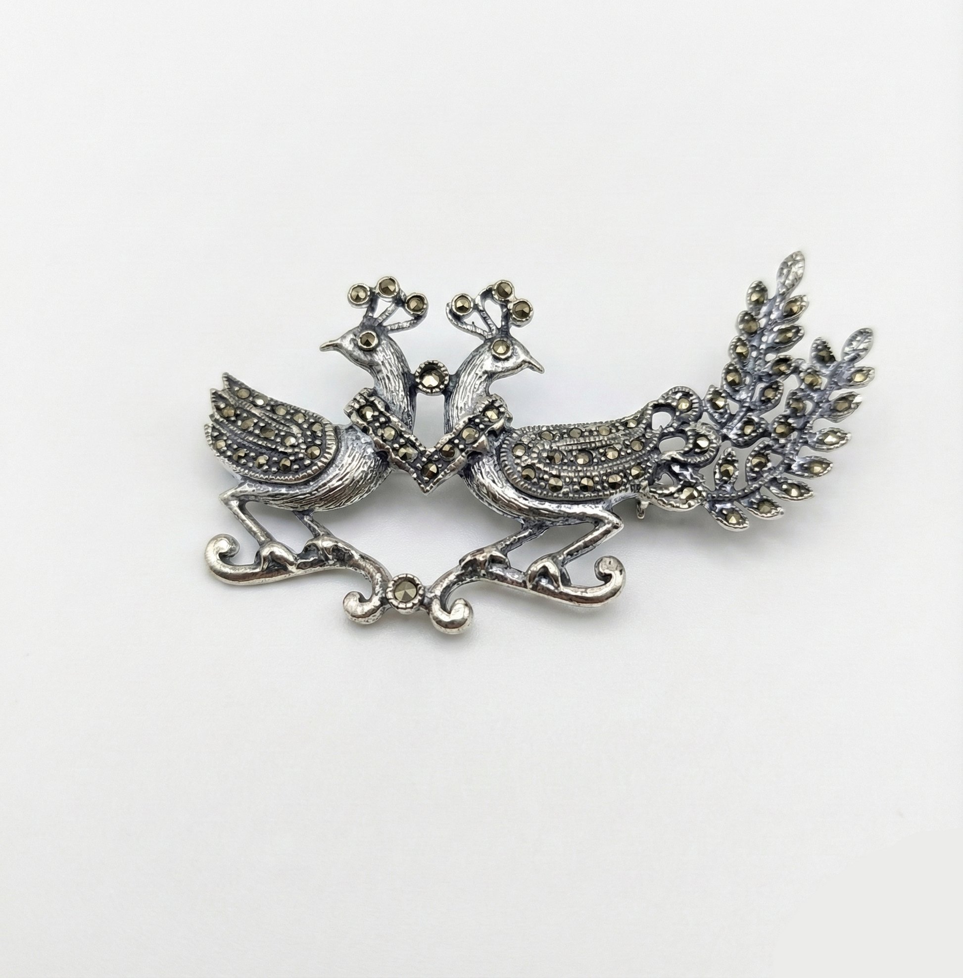 Silver peacock brooch on a white background