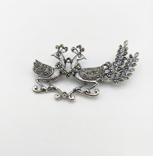 Silver peacock brooch on a white background