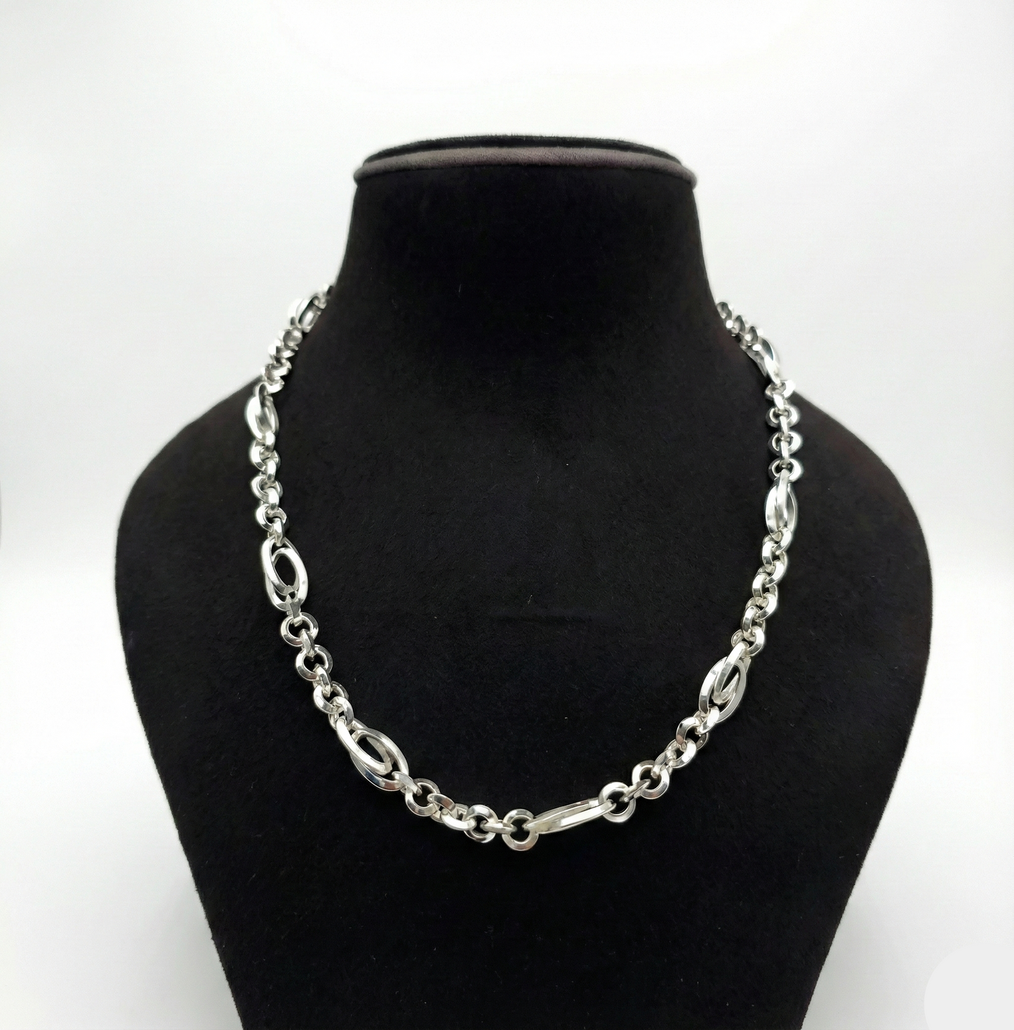 Silver chain necklace on a black mannequin bust against a white background