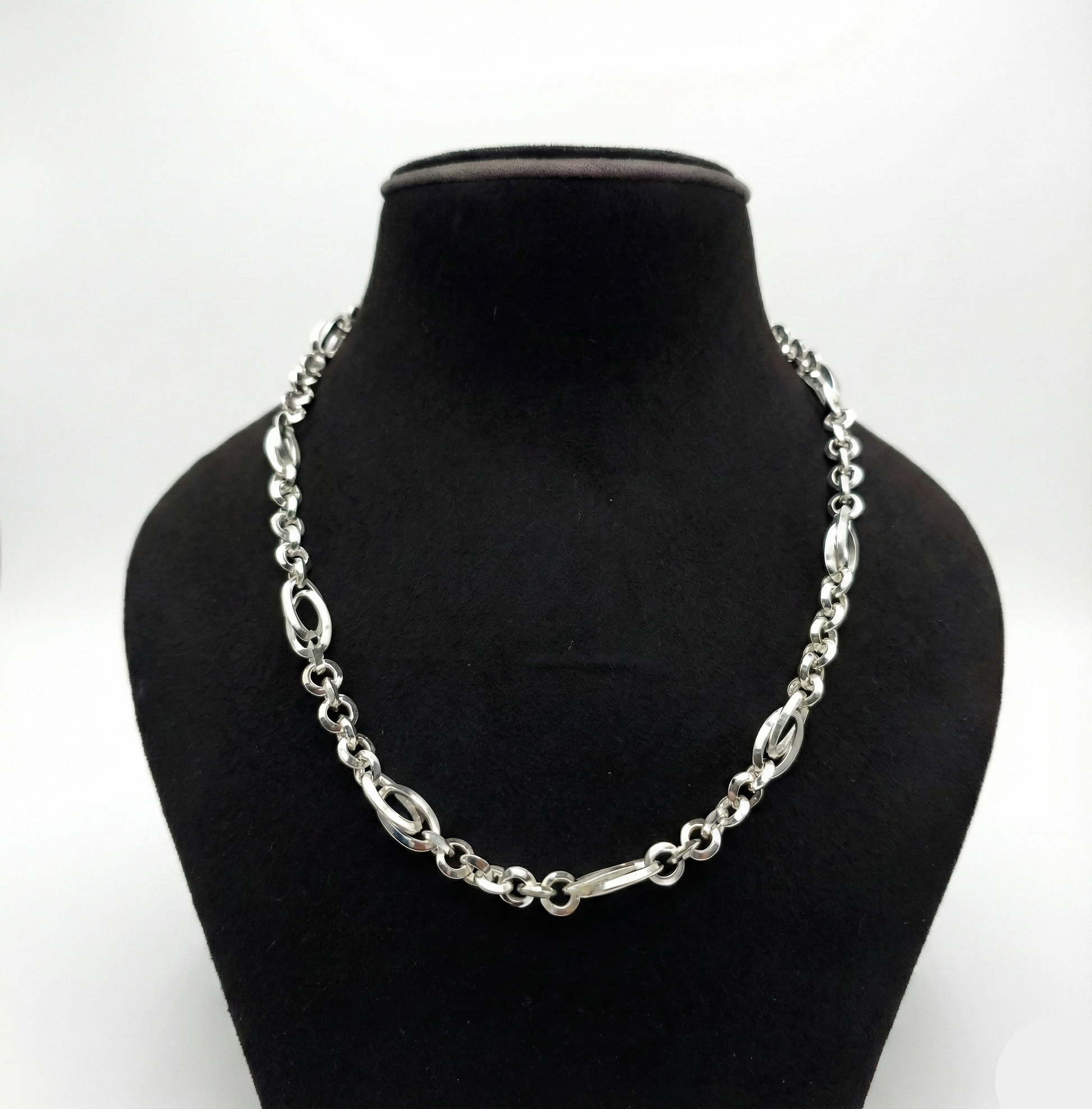 Silver chain necklace on a black mannequin bust against a white background