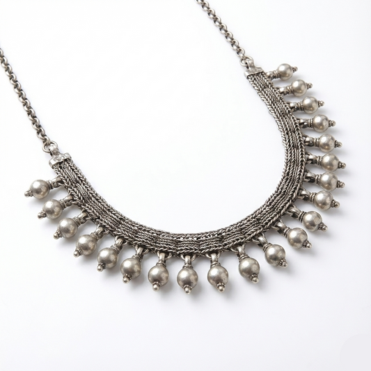 Silver necklace with multiple strands and hanging beads on a white background