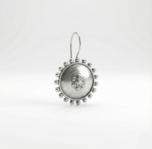 Silver earring with intricate design on a white background