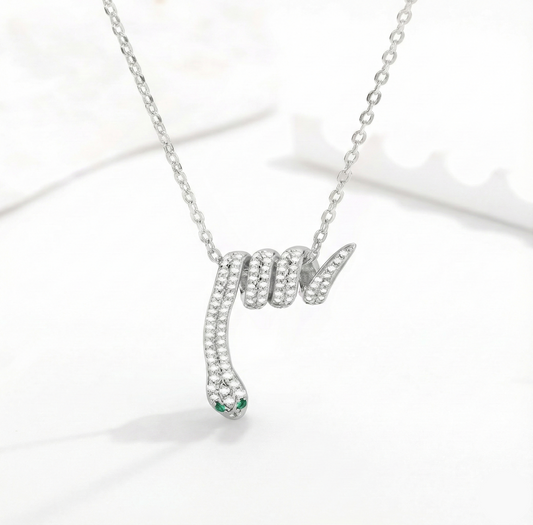 Silver snake-shaped pendant necklace with green gemstone on a white background