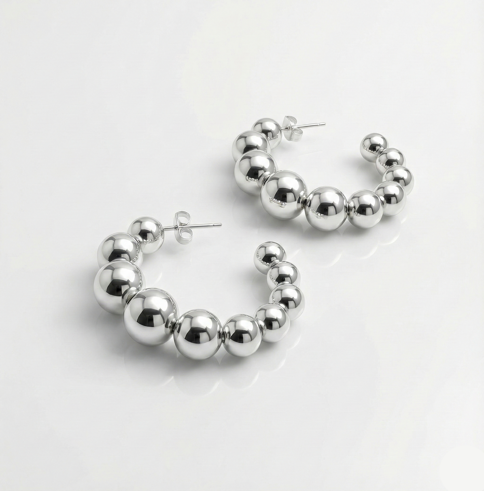 Silver hoop earrings with spherical beads on a white background