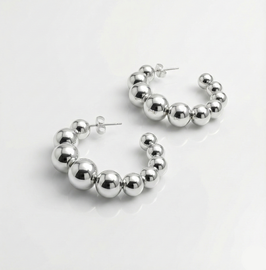 Silver hoop earrings with spherical beads on a white background