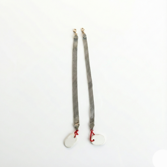 Pair of gray suspenders with red buttons on a white background