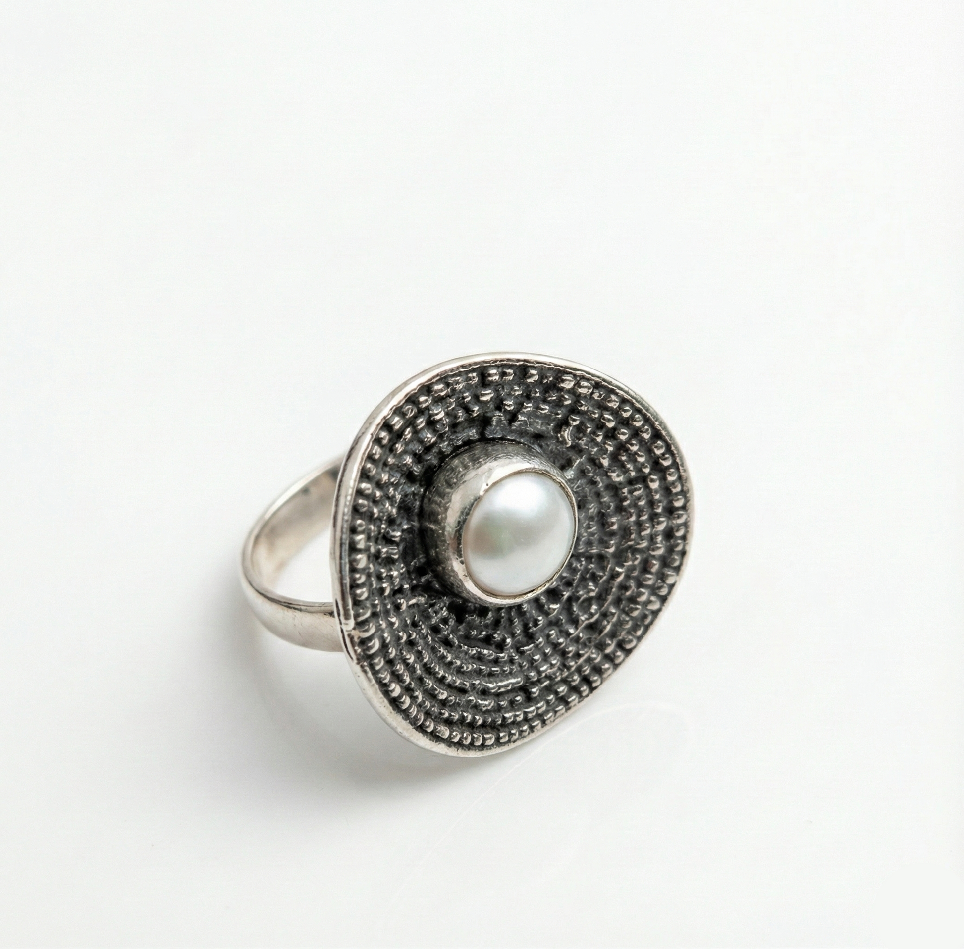 Silver ring with a pearl center on a white background