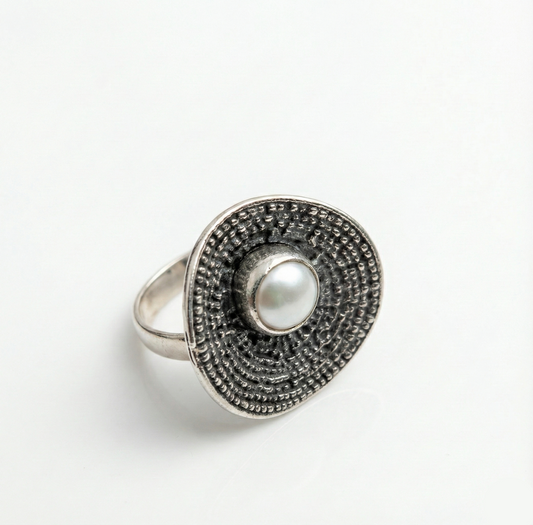 Silver ring with a pearl center on a white background