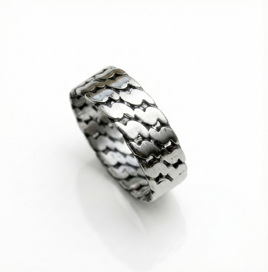 Silver ring with a textured pattern on a white background