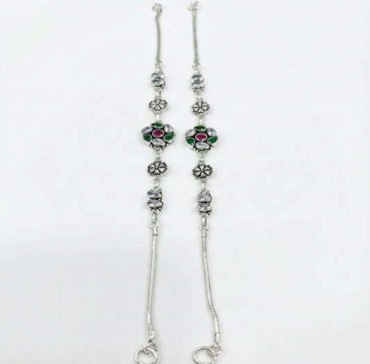 Silver floral anklets with gemstones on a white background