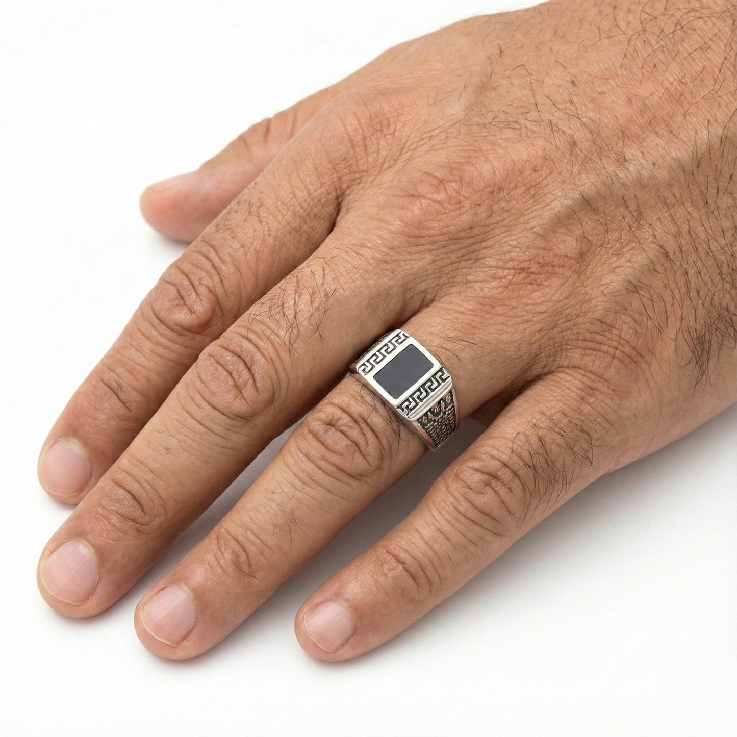 Hand wearing a silver ring with a black stone on a white background