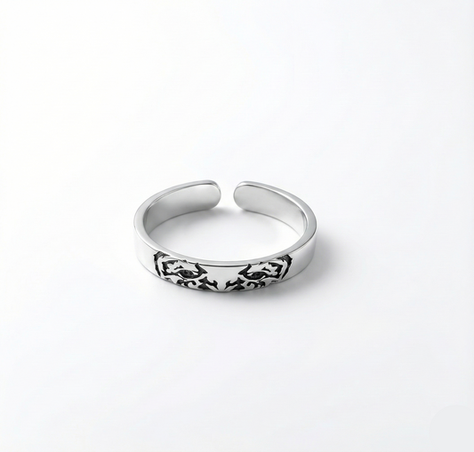 Silver ring with intricate design on a white background
