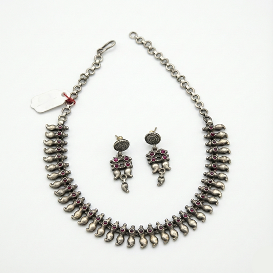 Silver necklace and earrings set on a white background
