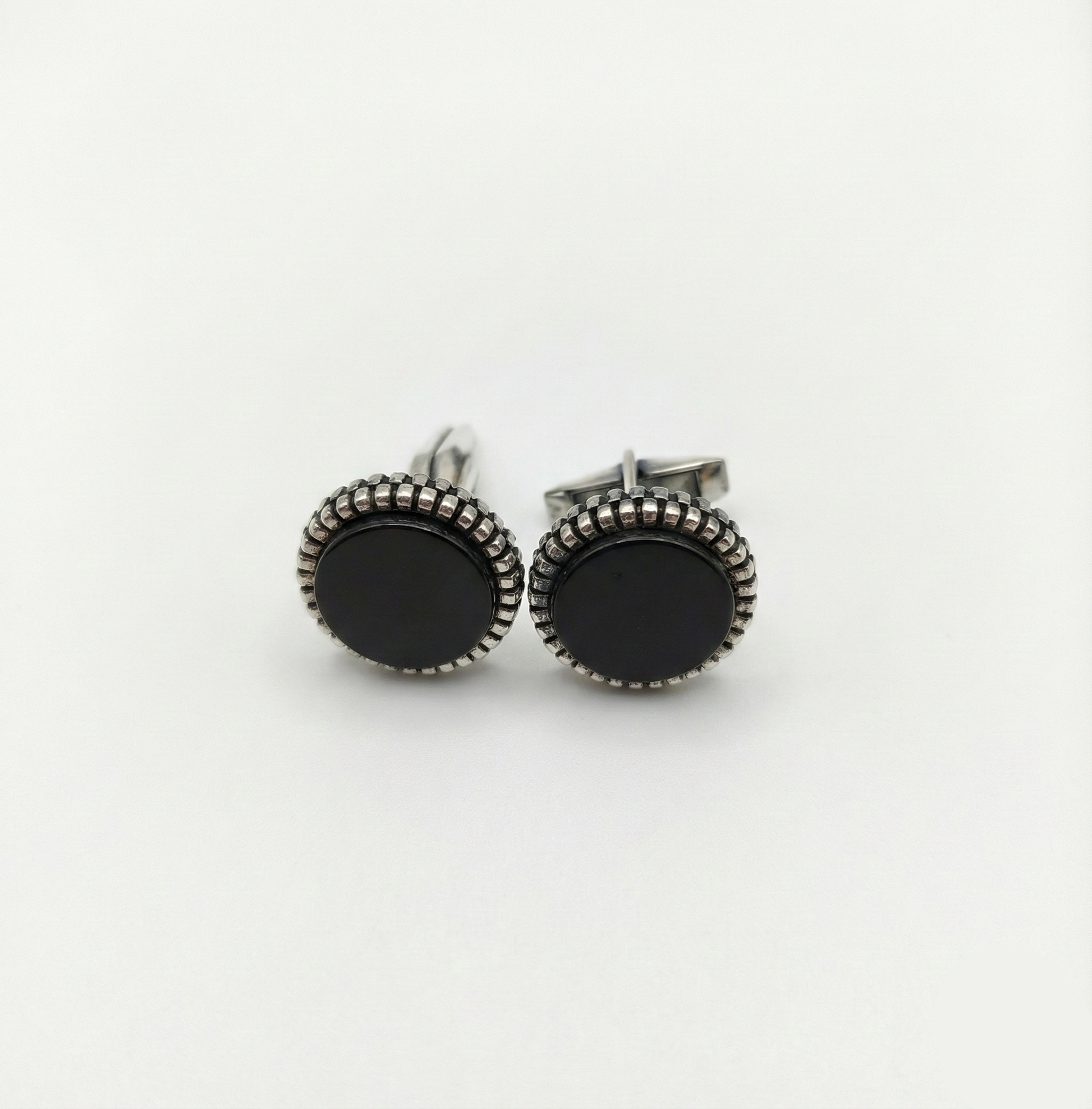 Pair of black round earrings with silver detailing on a white background