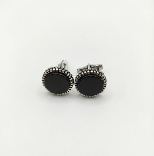 Pair of black round earrings with silver detailing on a white background