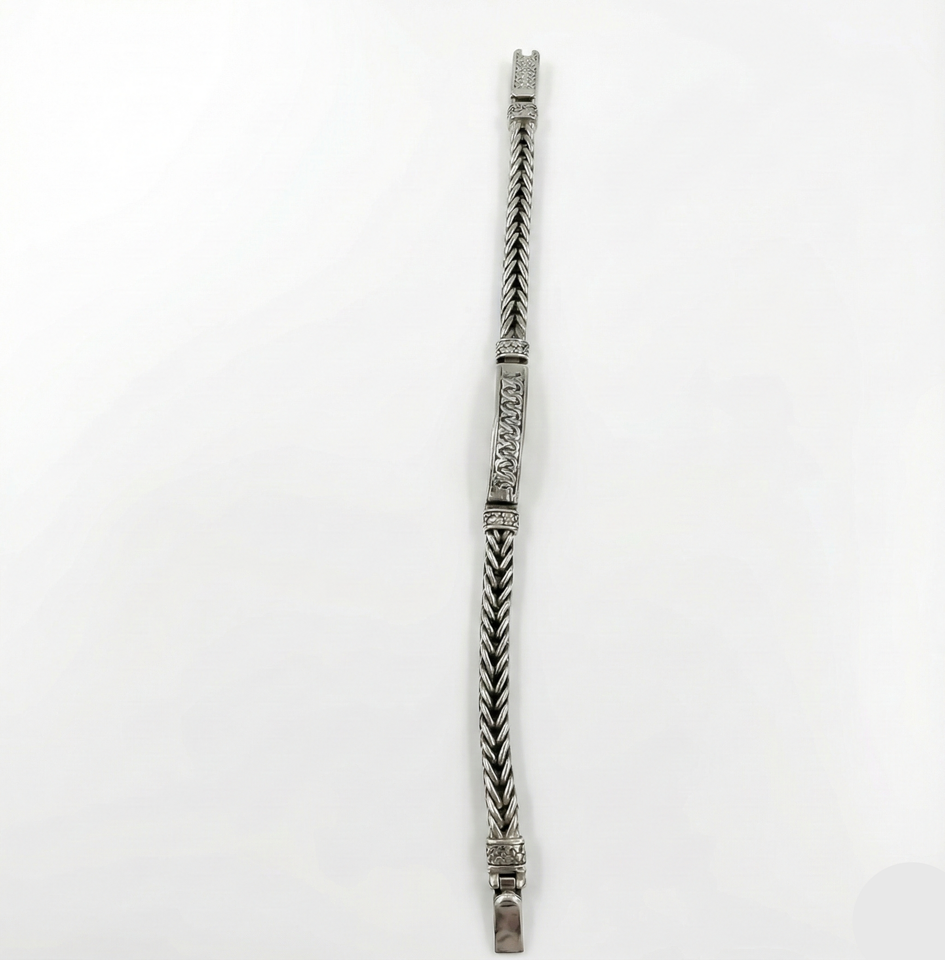 Silver bracelet with decorative pattern on a white background