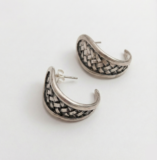 Silver hoop earrings with woven design on a white background