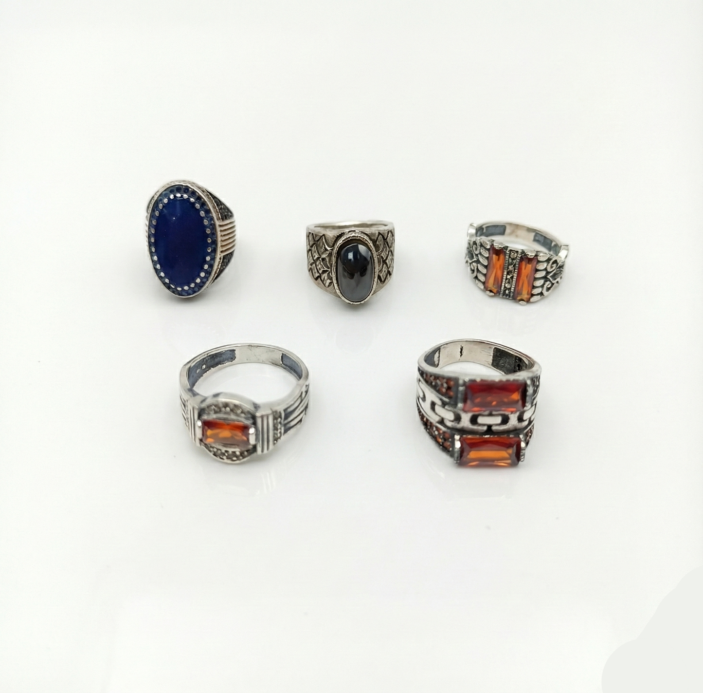 Five silver rings with gemstones on a white background