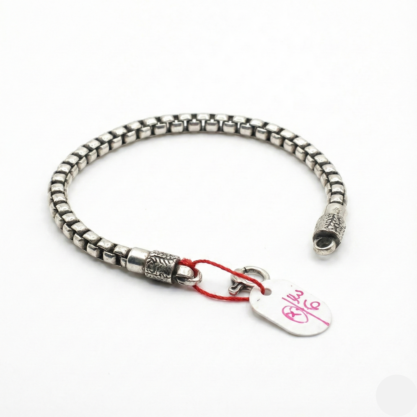 Silver bracelet with a heart-shaped tag on a white background