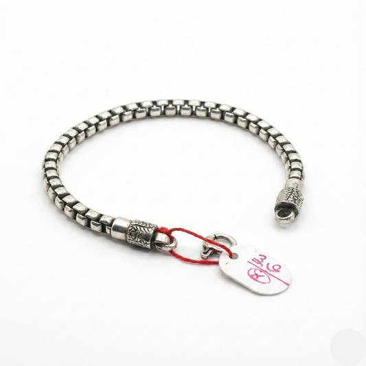 Silver bracelet with a heart-shaped tag on a white background