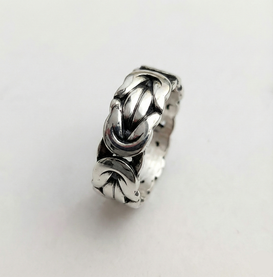Silver ring with intricate design on a light gray background