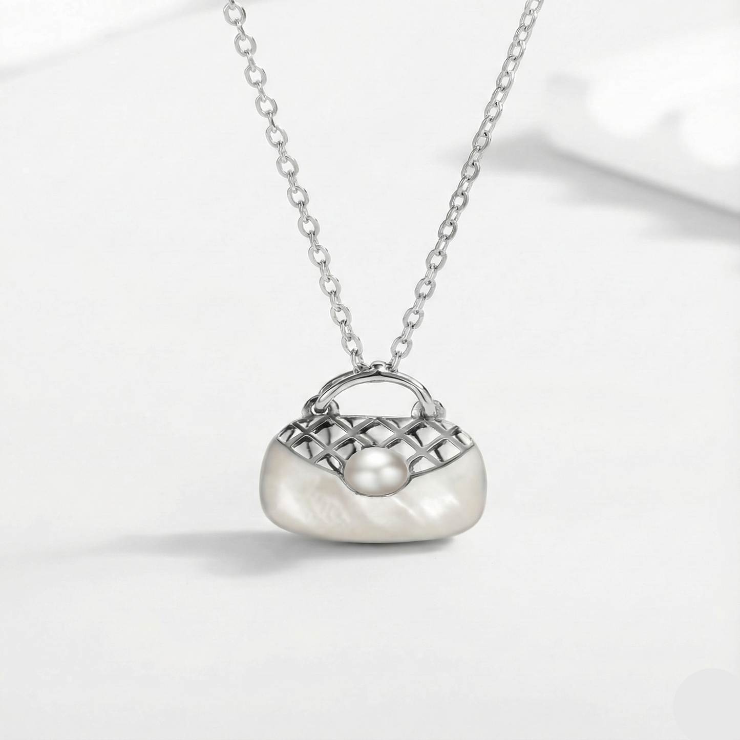 Silver necklace with a handbag-shaped pendant on a white background
