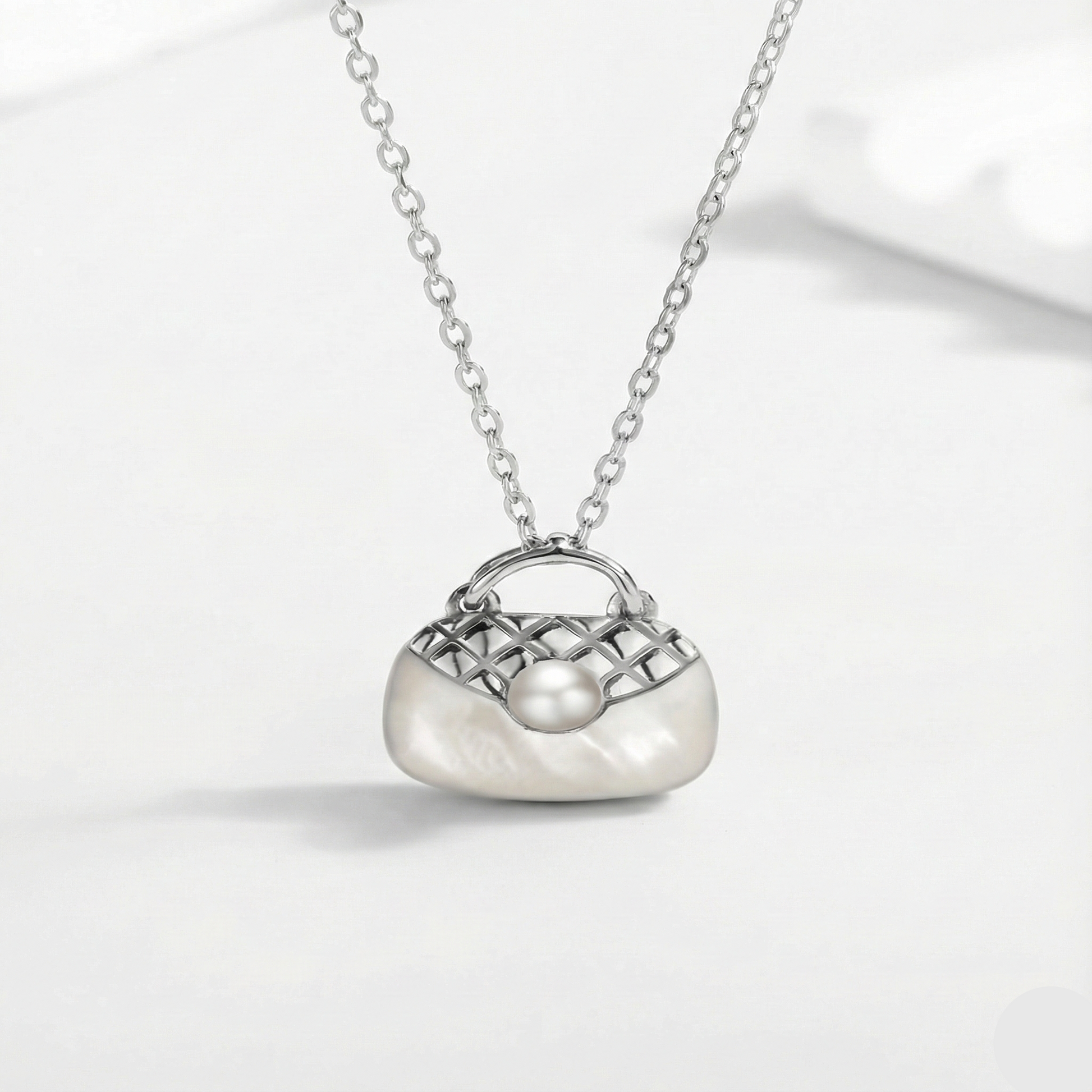 Silver necklace with a handbag-shaped pendant on a white background