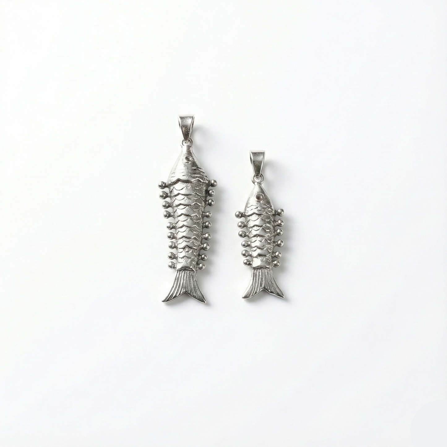 Two silver fish-shaped pendants on a white background