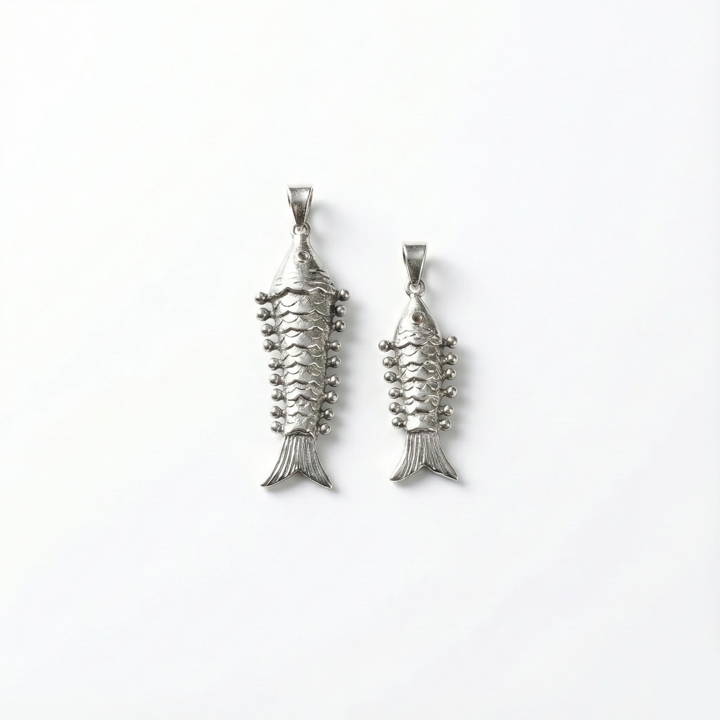 Two silver fish-shaped pendants on a white background