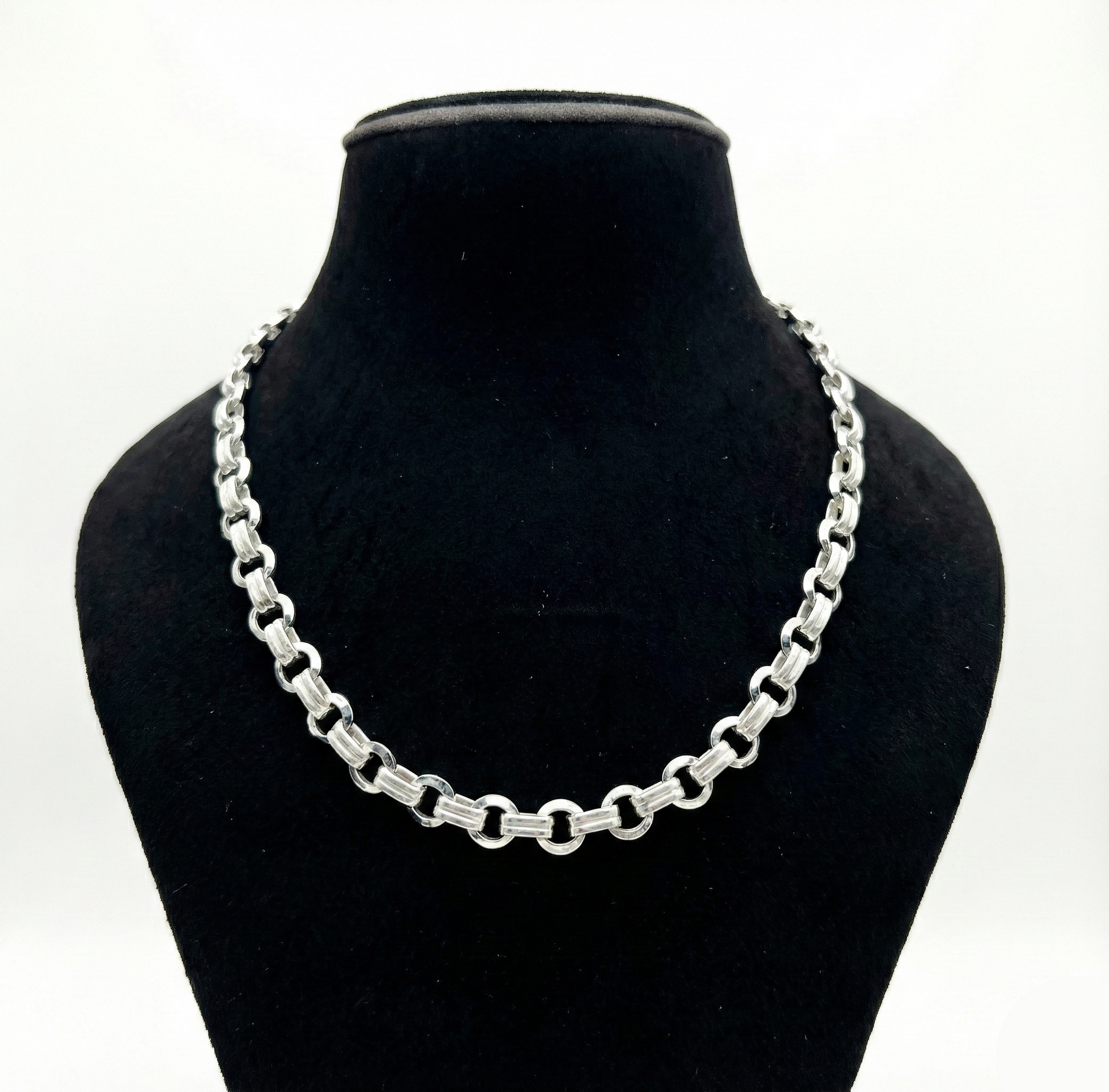 Silver chain necklace on a black mannequin bust against a white background
