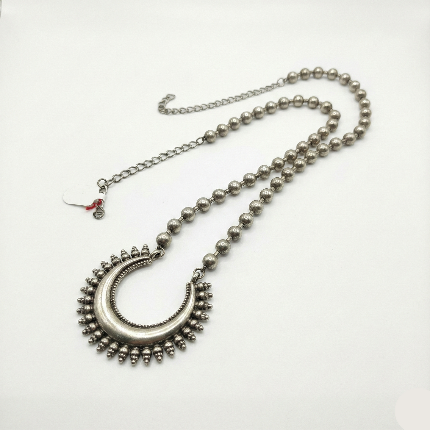 Silver necklace with a decorative pendant on a white background