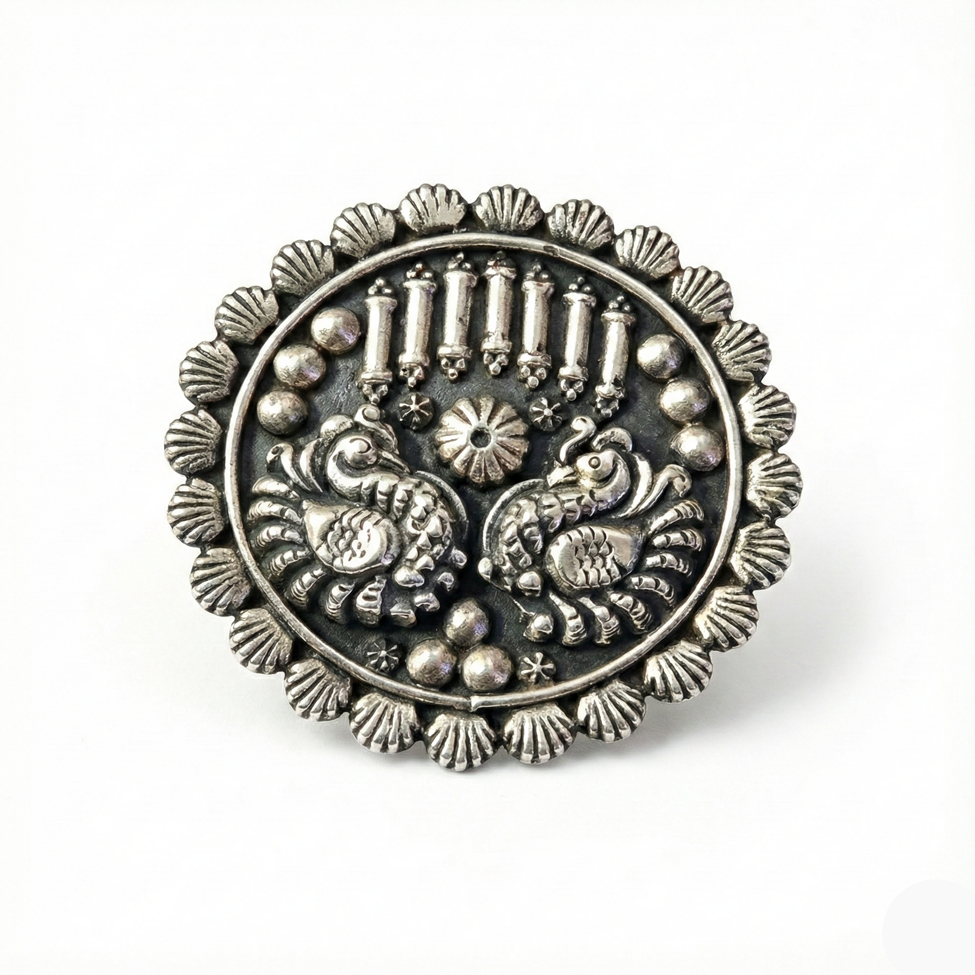 Silver brooch with intricate design on a white background